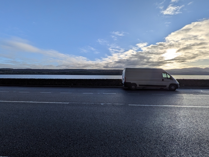 Side on view of the corgi couriers view at sunset in front of a loch in Scotland, part of a national delivery route